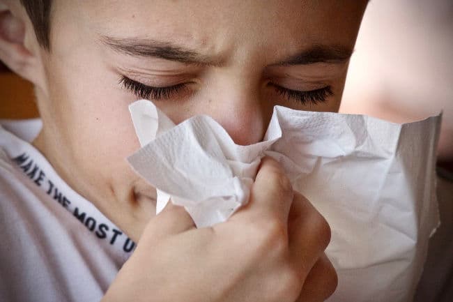 Boy with allergy symptoms sneezing
