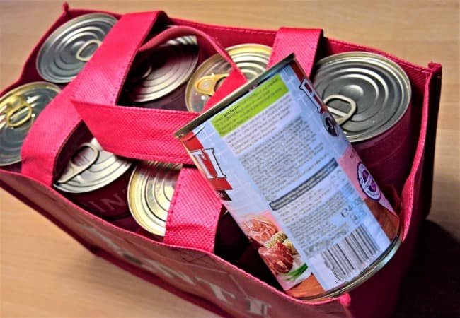 Bag full of dog food cans with one displaying ingredient label