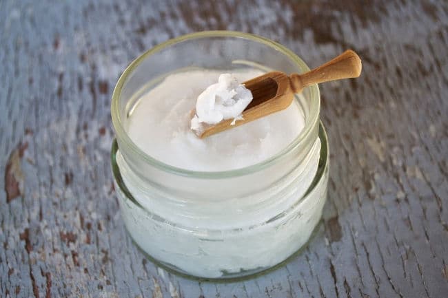 Jar of organic coconut oil with wooden scoop Jar of organic coconut oil with wooden scoop