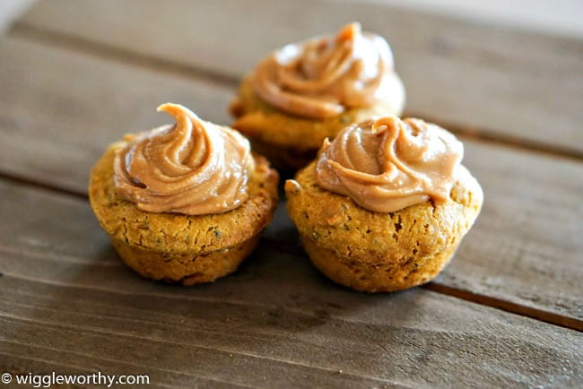 Three pumpkin carrot pupcakes with peanut butter frosting on wooden board Three pumpkin carrot pupcakes with peanut butter frosting on wooden board