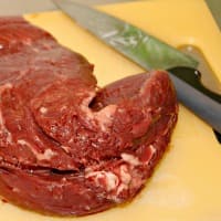 Raw beef on a cutting board with knife
